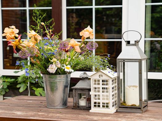 Ein Holztisch mit Blumenstrauß und Kerzenhaltern - Jetzt Immobilie kaufen