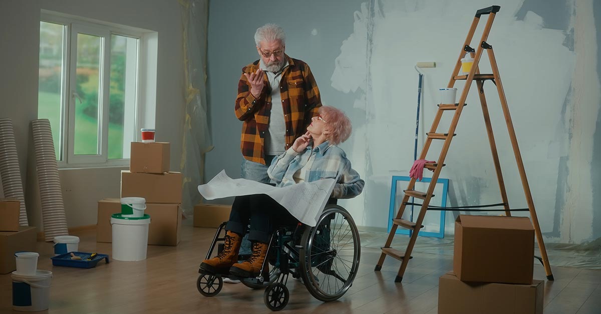 Älterer Mann und Frau im Rollstuhl sind in einer Wohnung, die gerade renoviert wird | Wohnen im Alter