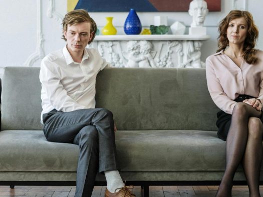Ein Paar hat die Scheidung beschlossen und sitzt unglücklich auf dem Sofa in seinem Wohnzimmer | Scheidungsimmobilie